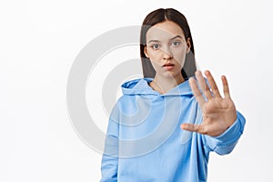 Please stop, enough, quit it. Young concerned woman extend hand and tell no, disagree, forbid or reject smth, taboo