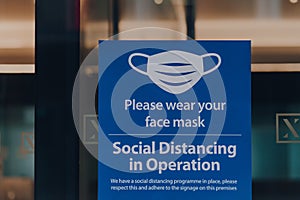 Please wear your face mask sign at the entrance of an office building in London, UK