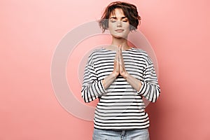 Pleased beautiful woman posing isolated over pink wall background meditate