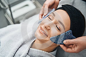 Pleased beauty salon customer receiving a facial massag