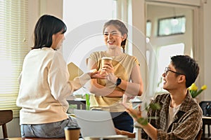 Pleased business colleagues having conversation during coffee break at co working space