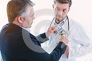 Pleased dishonest doctor taking a bribe