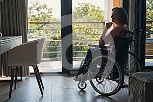 Pleased female wheelchair user looking inside a house photo