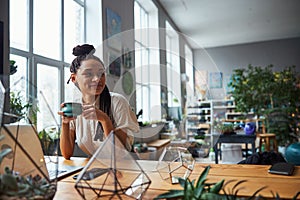 Pleased florist with cornrows daydreaming during the tea break