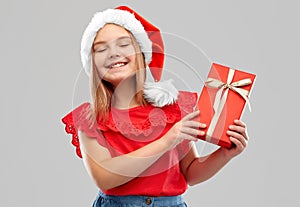 Pleased girl in snata hat with christmas gift