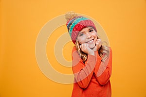 Pleased girl in sweater and hat reclines on her arms