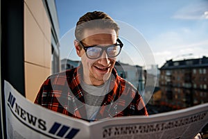 Pleased guy reading the newspaper outside