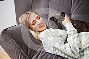 Pleased lady holding bulldog on her chest