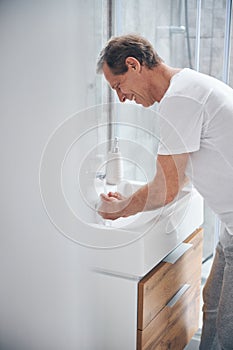 Pleased man leaning over a ceramic wash basin