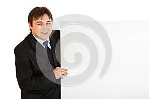 Pleased modern businessman holding blank billboard