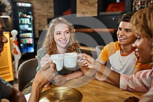 pleased multiethnic buddies clinking coffee cups