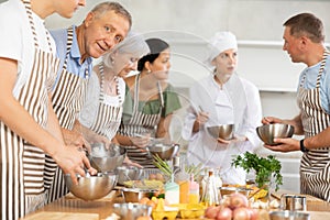 Pleased old man attendee of cooking course learning how to mix sauce