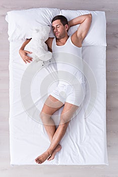 Pleased and relaxed young man sleeping on bed