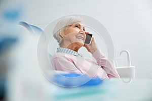 Pleased retiree chatting on cell phone at clinic