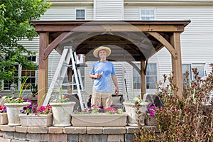 Pleased satisfied man staining a new gazebo