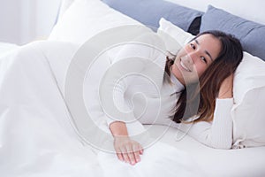A pleased sleeping on the side young woman smiling softly in bed