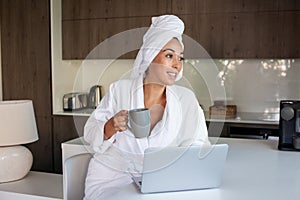 Pleased woman drinking coffee at home