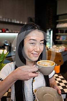 Pleased woman posing for the camera with a caffeinated drink