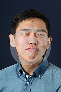 Pleased young Asian man making face photo