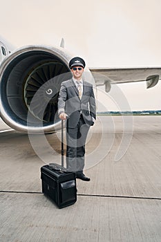 Pleased young pilot with his baggage posing for the camera