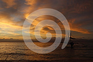 Pleasure boat against the backdrop of a cloudy golden sunset at sea.