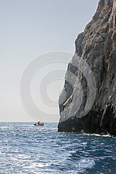 Pleasure boat circumnavigating a cliff. Cliffside