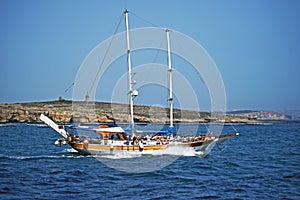 A pleasure boat with lots of sightseers aboard heading back to the sea . photo