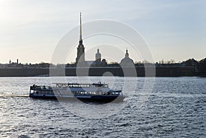 Pleasure boat on the Neva river opposite the Peter and Paul fortress at sunset