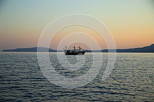 Pleasure boat on the sea against the background of mountains at sunset