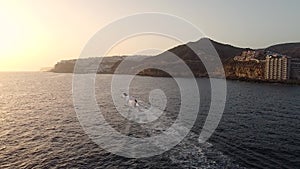 Pleasure boats sailing along the rocky beach, aerial view of the coastline at sunset. Gran Canaria