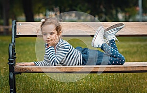 Pleasure little girl lying on bench