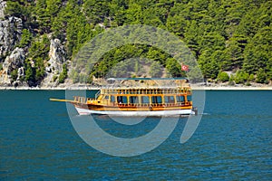 Pleasure motor yacht in the Green canyon against a continuous array of trees.