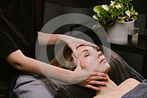 Pleasured woman receiving facial massage in a beauty salon by fingers