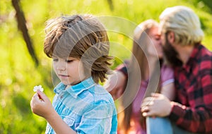 Pledge of love. Little child with couple kissing on background. Small child hold spring flower. Cute boy child sunny day