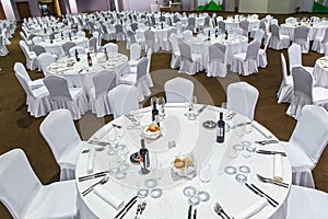 Plenty of big round tables and chairs covered with white tablecloth are set for a meal in the Gorky Gorod restaurant. Wide angle i