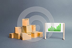 Plenty of cardboard boxes and whiteboard with green positive trend chart. rate growth of production of goods and products