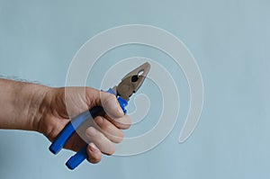 Pliers with blue dielectric grips in a male hand