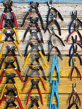 Pliers with colored handles hanging by rows on the wall. Tools board. Concept of organizing