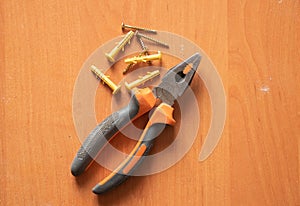 Pliers and self-tapping screws lie on a dirty wooden table, repair