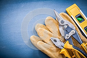 Pliers tin snips construction level safety gloves on wooden boar