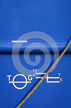 Plimsoll mark on blue rustproof steel hull surface of large vessel with mooring rope