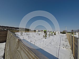 Plot of land in winter. Construction of a private house. Fence on the land in winter