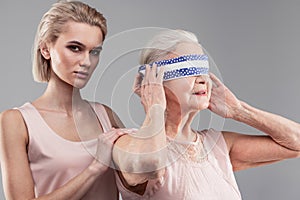 Plotting blonde beautiful girl blocking vision of old helpless woman