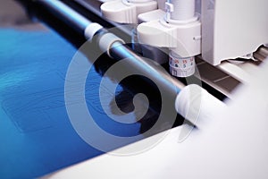 plotting machine cuts high detailed tiger striped lettering from black adhesive foil in blue dazzling light