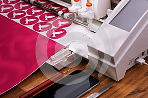 plotting machine cuts pink peace dove stickers from adhesive foil on cosy workplace