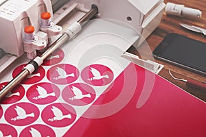 plotting machine cuts round peace dove stickers from pink adhesive foil