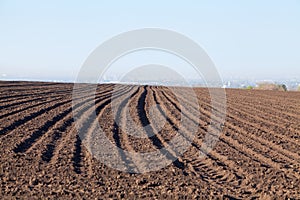 Ploughed field in spring, agricultural background, fog over the city in the background. Ukraine