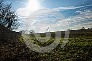 Ploughed fields in winter, with distant wind turbine and dew drenched grass in foreground