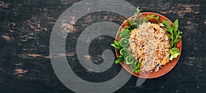 Plov Rice with meat and vegetables on a plate. Uzbek cuisine. On a wooden background. Top view