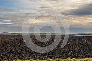 Plowed field ready for sowing. There are clouds over the landscape